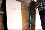 A Tesla battery attached to the outside of a home.