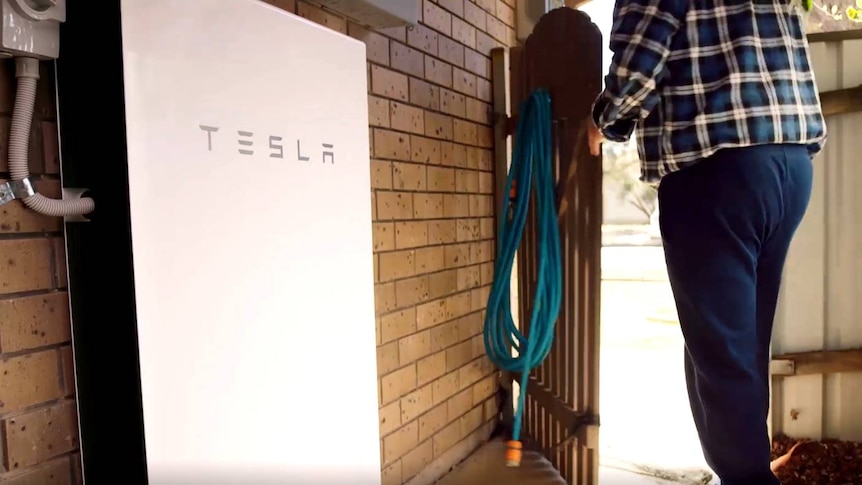 A Tesla battery attached to the outside of a home.