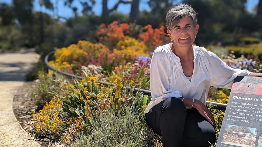 A smiling woman in front of a glorious native Australian garden.