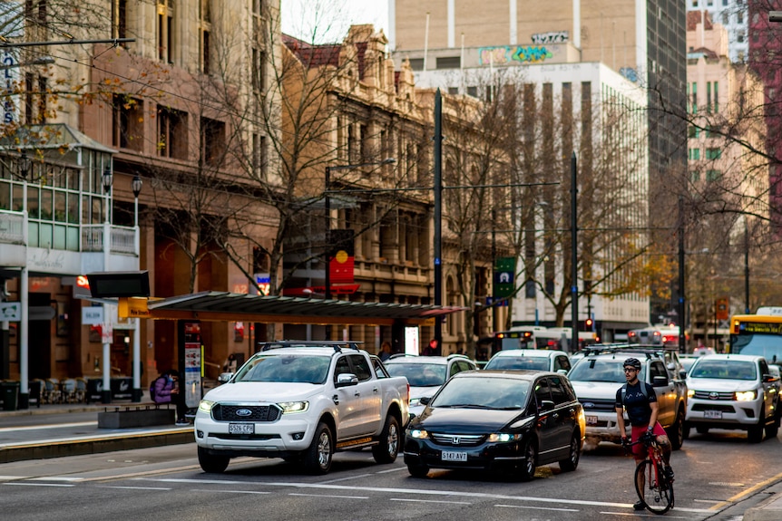 Cars and a cyclist in a CBD street with a tram stop in the middle
