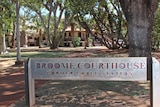Exterior of a building surrounded by leafy trees. A sign says Broom Courthouse.