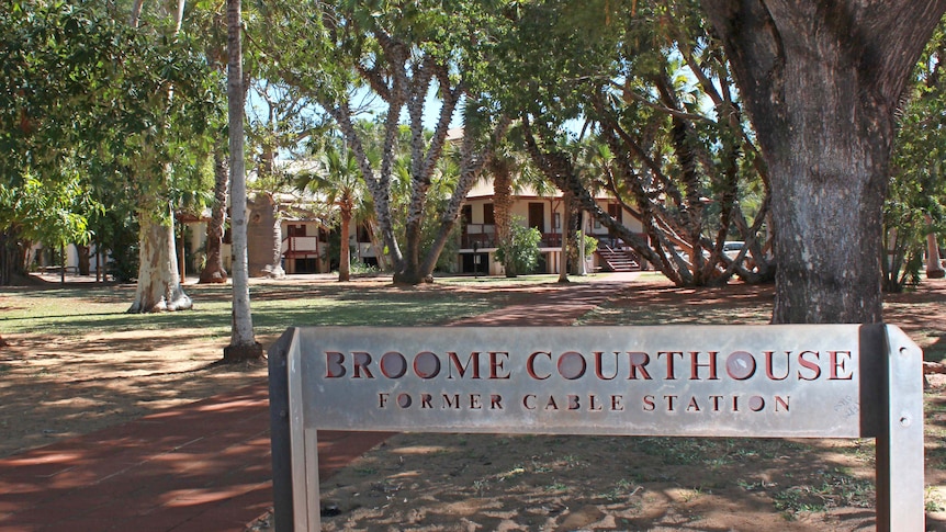Exterior of a building surrounded by leafy trees. A sign says Broom Courthouse.