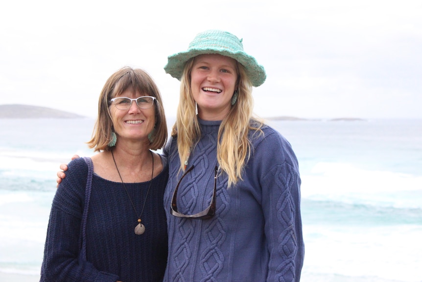 The pair stand on the beach wearing earrings made from marine debris, and Sam wears a marine debris hat