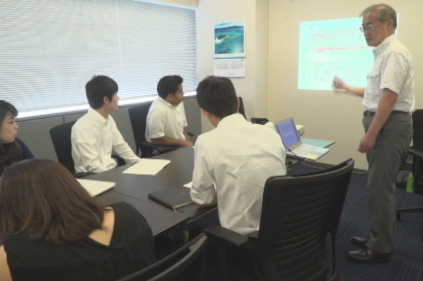 Sakae Kajita teaches younger staff in an office.