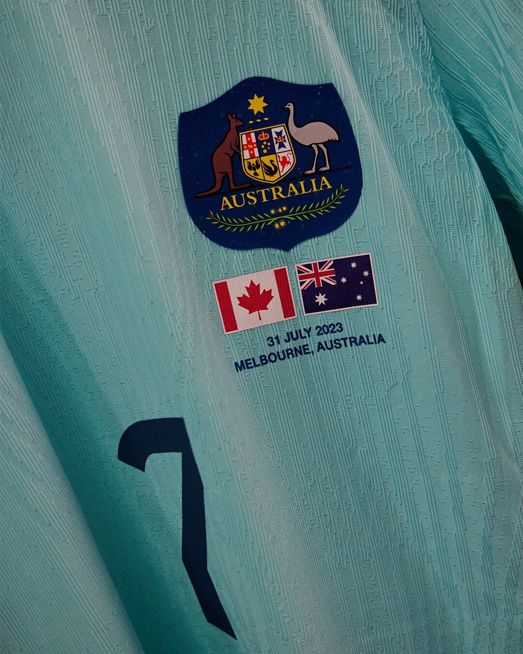 A close up for the turquoise blue Matildas jersey with the Australian and Canadian flag and the July 31 date