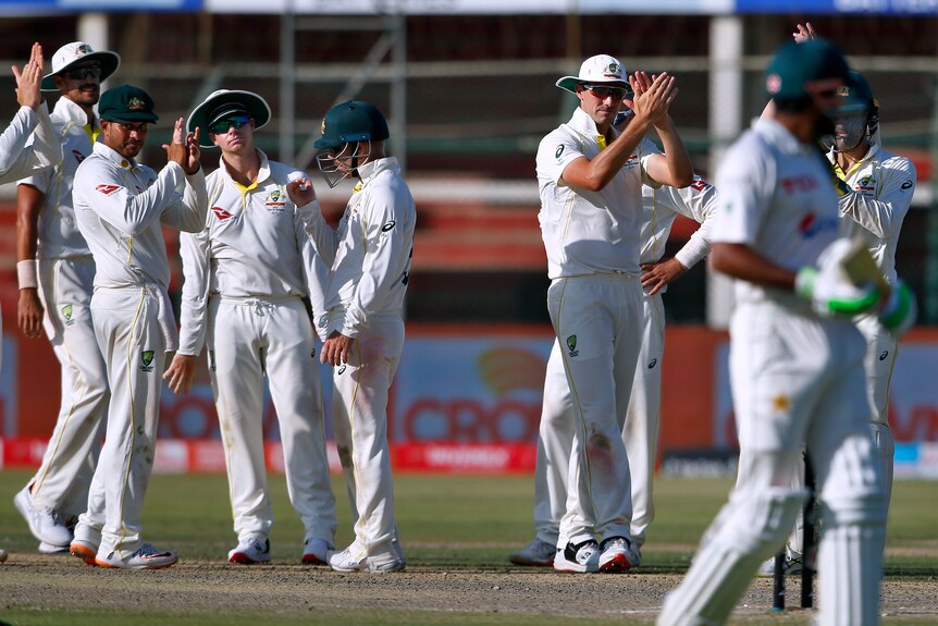 Pakistan batsman Babar Azam looks back over his shoulder as Australian cricketers clap him off after a Test innings of 196.