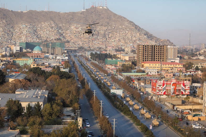 A military helicopter is seen above a military parade in Kabul. 
