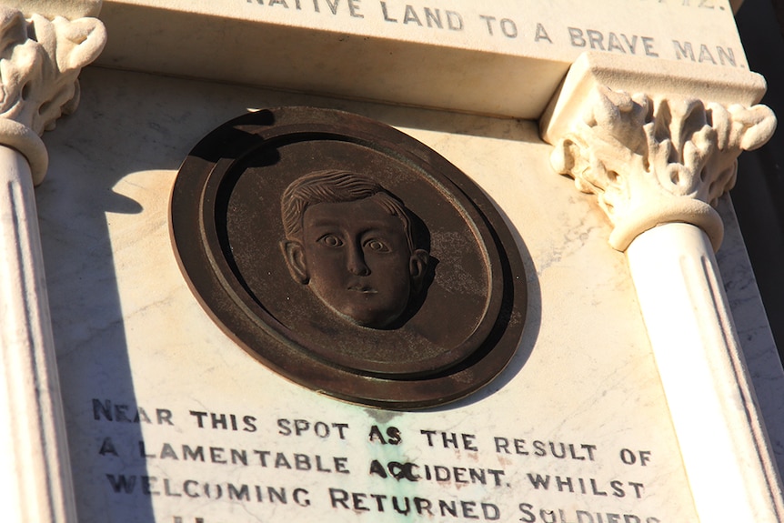 Metal bust of Hector Vasyli on a stone tablet.