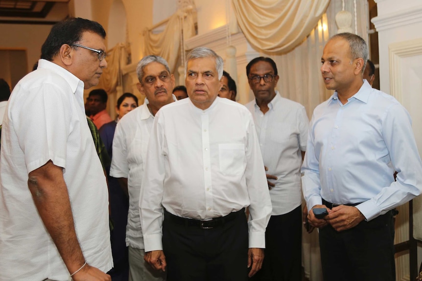 a group of men with white shirts stand in a room