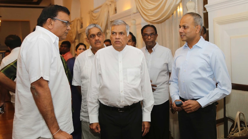 a group of men with white shirts stand in a room