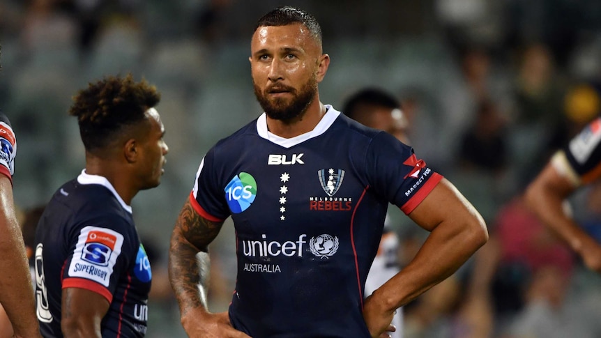 Quade Cooper stand with his hands on his hips looking ahead during a break in play for the Rebels.