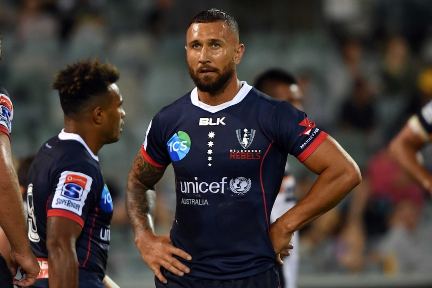Quade Cooper stand with his hands on his hips looking ahead during a break in play for the Rebels.