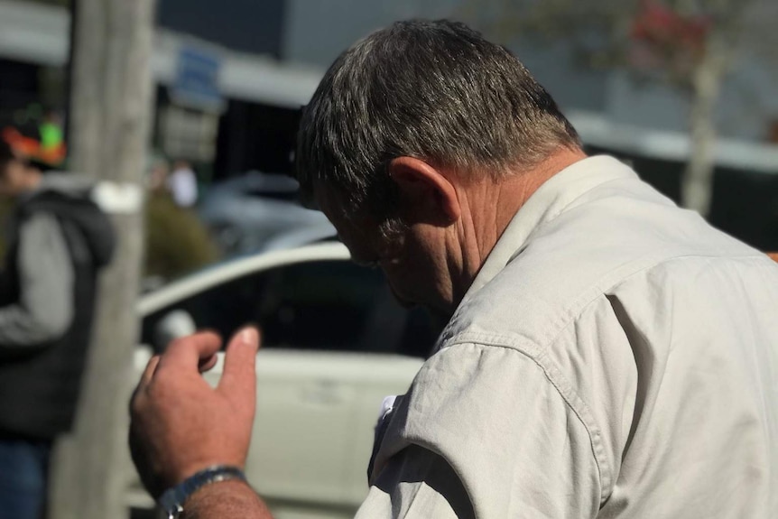 Murray Silvester tries to hide his face from cameras outside the Sale Magistrate Court.