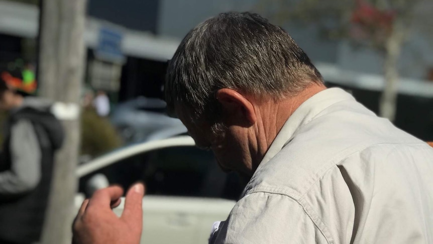 Murray Silvester tries to hide his face from cameras outside the Sale Magistrate Court.