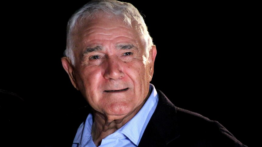 A smiling Tito Teraci poses for a photo against a black background.