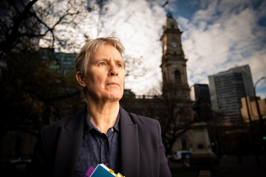 A woman with short blonde hair in dark top looking serious