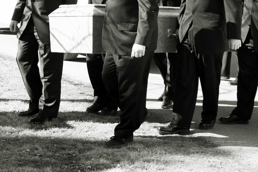 A group of men in suits carrying a coffin