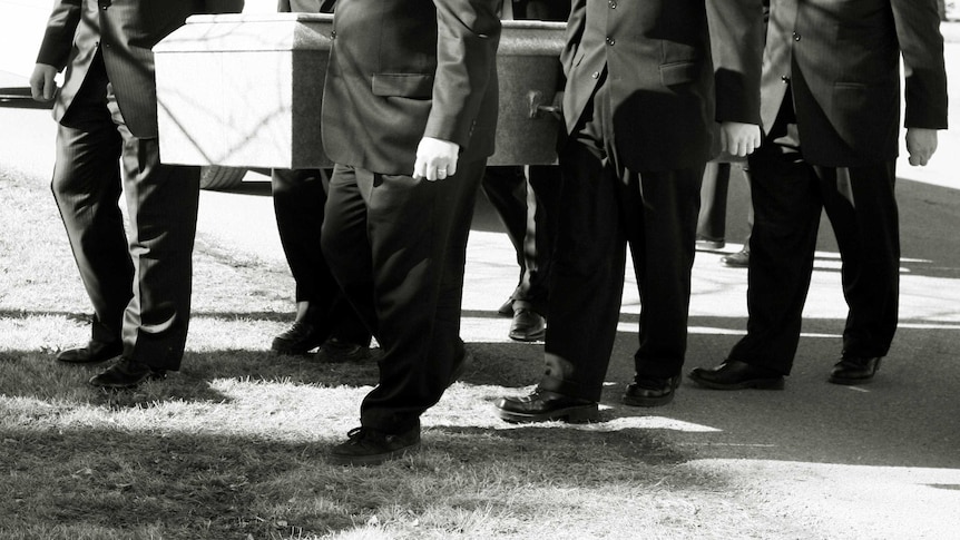 A group of men in suits carrying a coffin