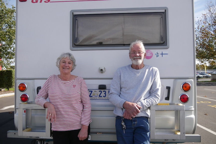 Couple stand at the back of their caravan