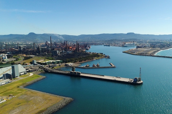 Une vue aérienne d'un port et d'une mine, ciel bleu et eaux turquoises.