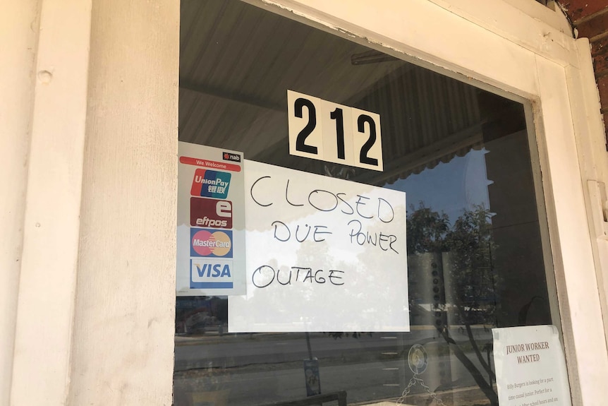 A glass door has a sign reading "Closed due to power outage"