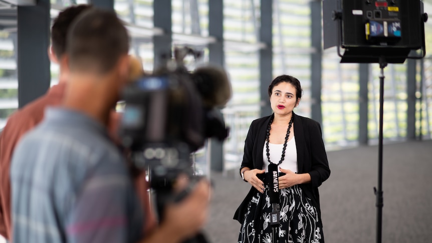 NT Education Minister Lauren Moss speaking in front of cameras at a press conference. 