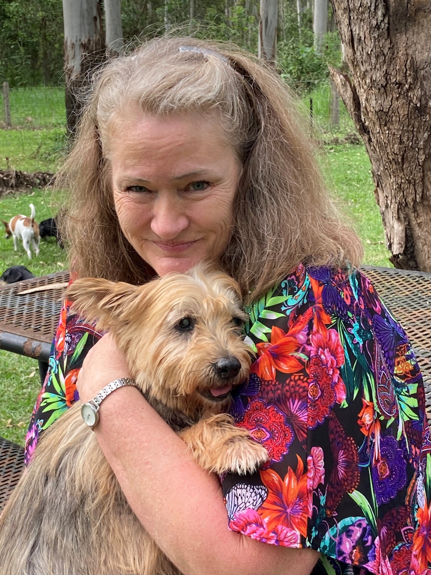 A smiling woman holding a small dog.