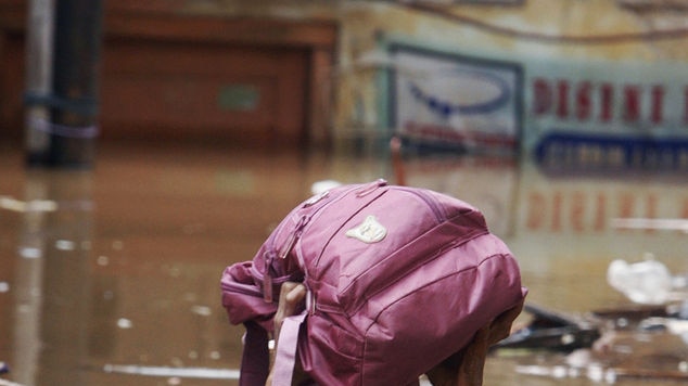 A man and his daughter use a rubber tyre to float away from their flooded housing complex