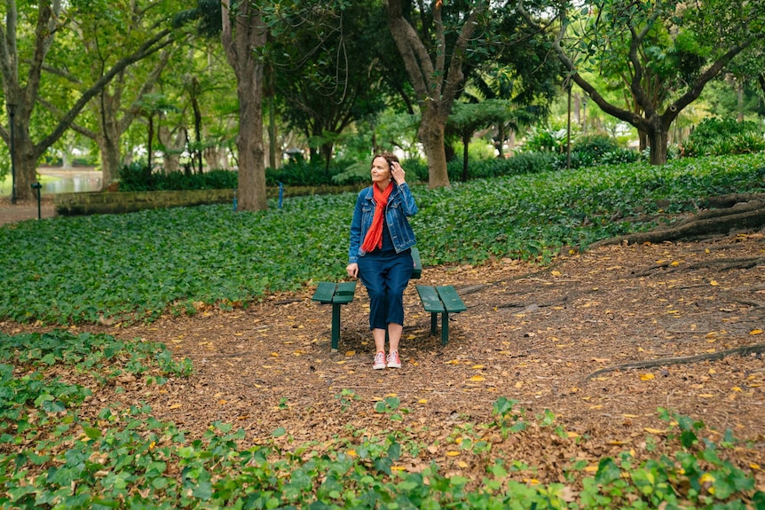 Andrea Hammond sits on a park bench surrounded by greenery.