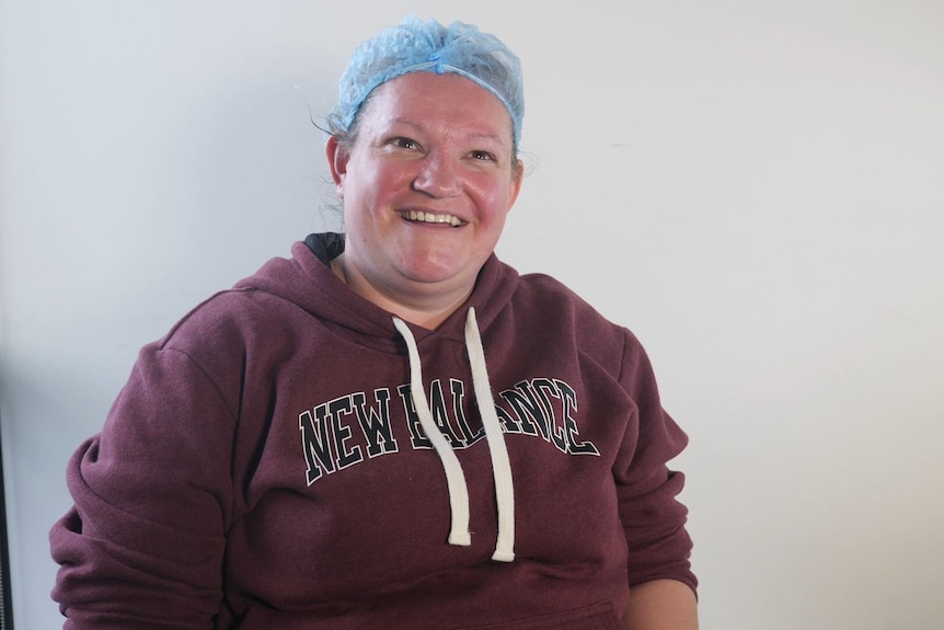 A woman wearing hair net smiles at the camera.