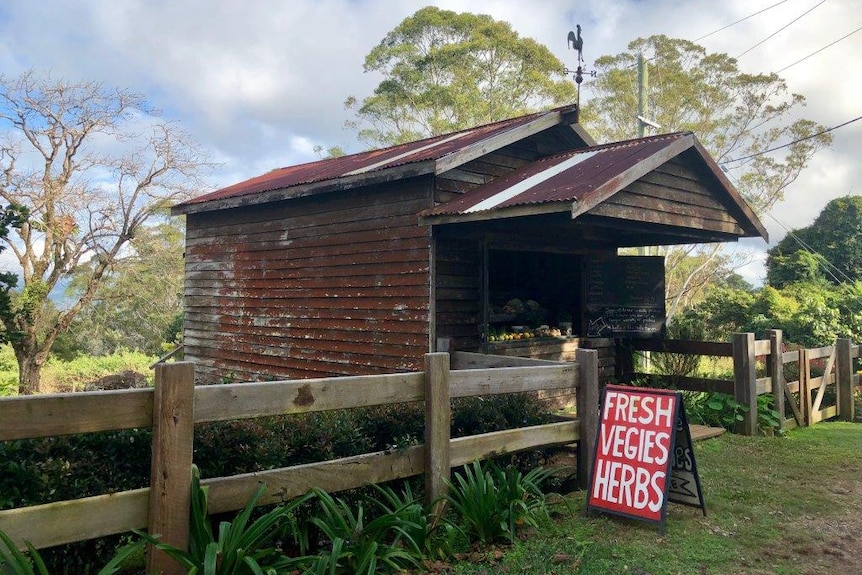 Rustic old shed with a fruit and veg sign out the front.