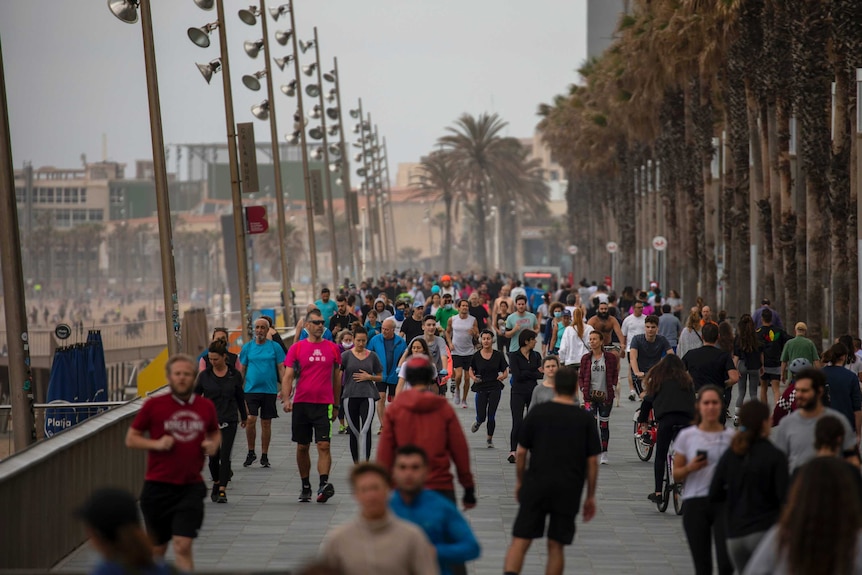 A crowd of people walk on a footpath