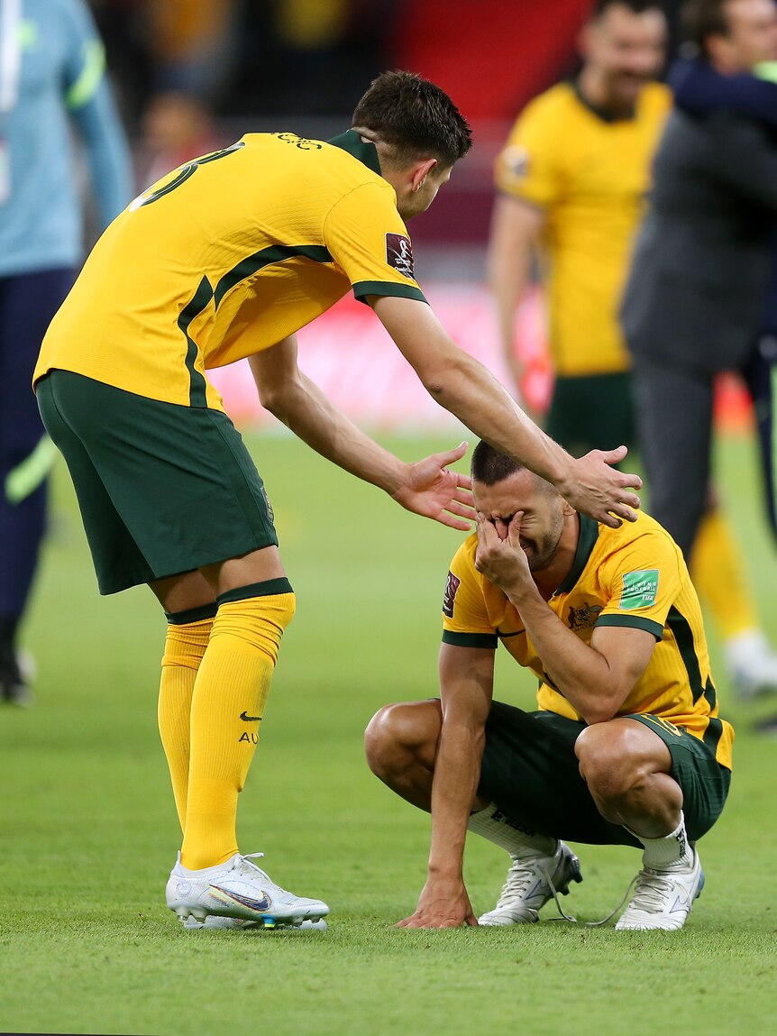 Two male soccer players wearing yellow and green celebrate after winning a game