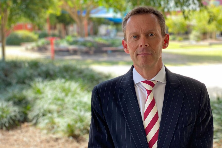 Man in suit in front of green area