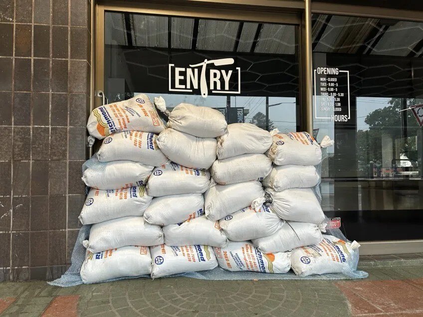 about twenty white sandbags staked up at a glass door. 