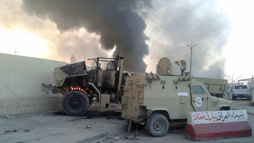 Damaged vehicles belonging to Iraqi security forces on a street in Mosul on June 10, 2014.