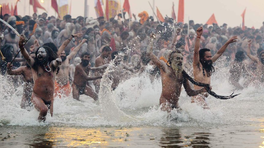 Sadhus run into the water at the confluence of the Yamuna and Ganges rivers