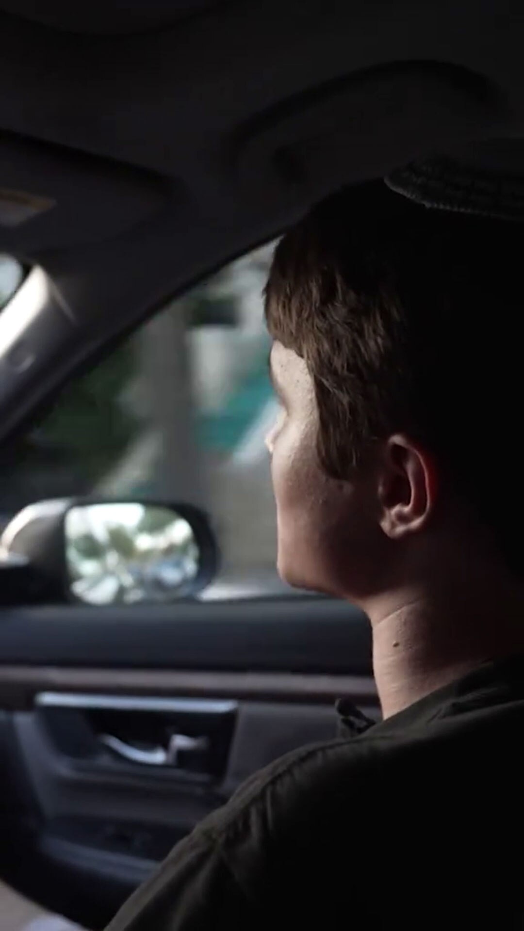 Photo taken from inside a car shows a man from behind with side mirror visible in background