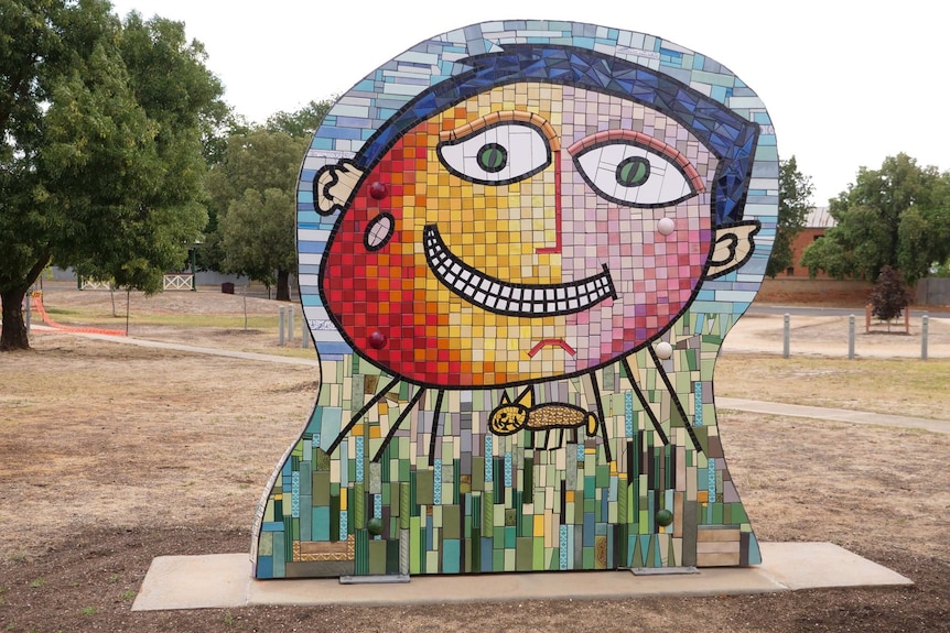 A large colourful mosaic sculpture of a smiling boy's face