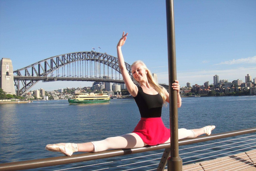 Former ballet dancer Sophia Bender does the splits on a balustrade in front of the Sydney Harbour Bridge