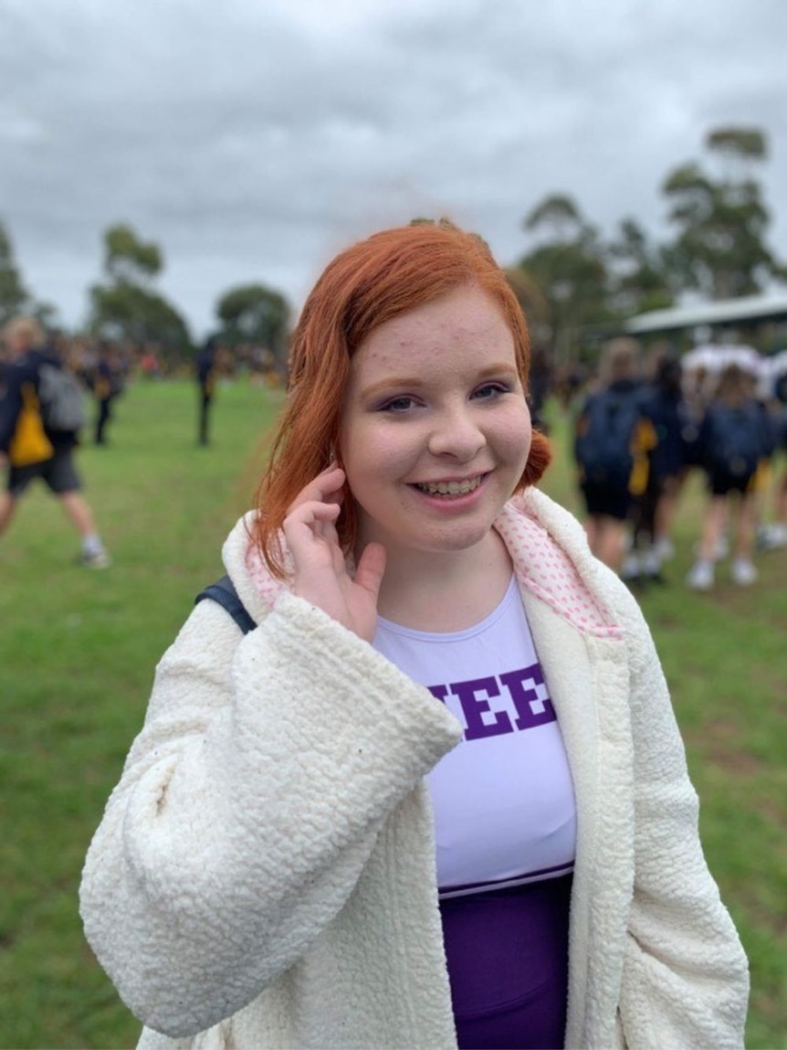 A young woman in a cheerleading costume smiles