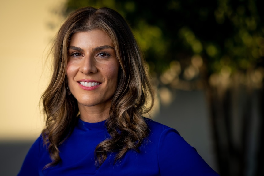 Former Liberal staffer & lawyer Anna Finizio, who is wearing a royal blue top, with her long brown hair tumbling down the front.