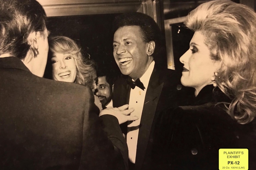 Donald Trump gestures with his hands to a man and two women (including E Jean Carroll, second from left).