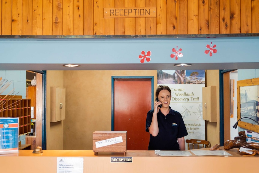 A woman on the phone behind a motel desk.