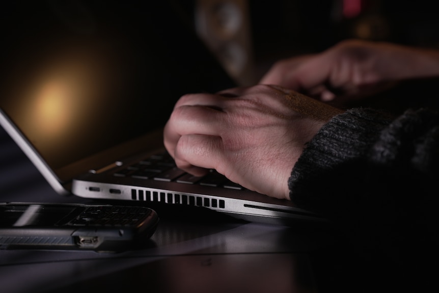 A man's hands tapping on a laptop keyboard.