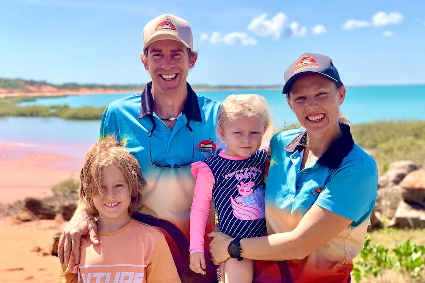 A smiling family stand in front of a bay