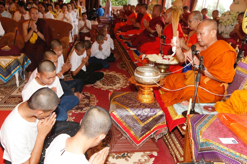 Buddhist monk sprinkles water to members of Wild Boars soccer team for good luck.