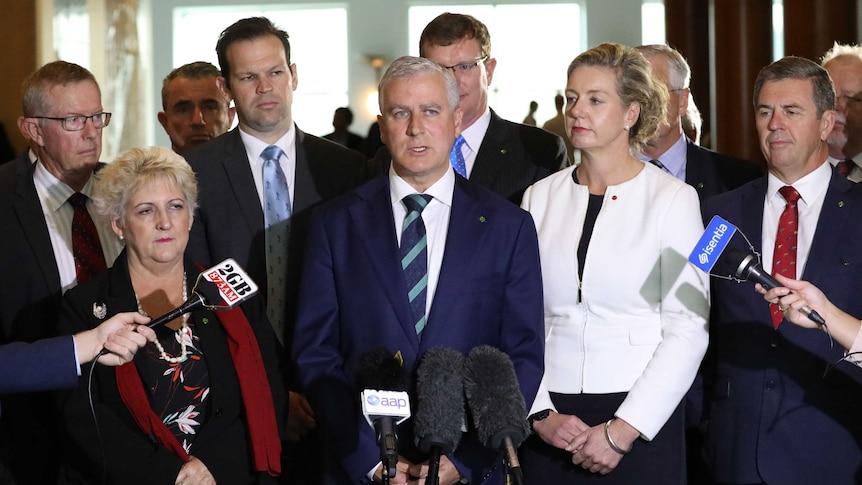 Nationals watch leader Michael McCormack during a press conference. They all have blank expressions on their faces.