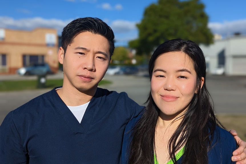 A close-up portrait of Chris Tan and Amelia Yu taken outside in their vet uniforms with a street behind them 