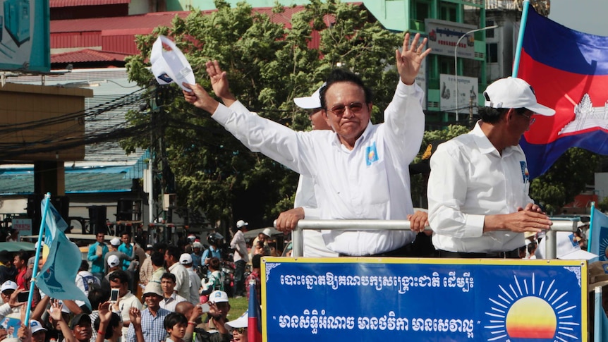 Cambodian Opposition party president Kem Sokha puts his arms in the air as he greets his supporters from a truck.